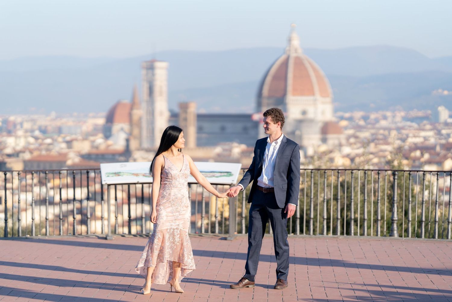 Couple enjoying a romantic moment at Piazzale Michelangelo overlooking the stunning Florence cityscape at sunset.