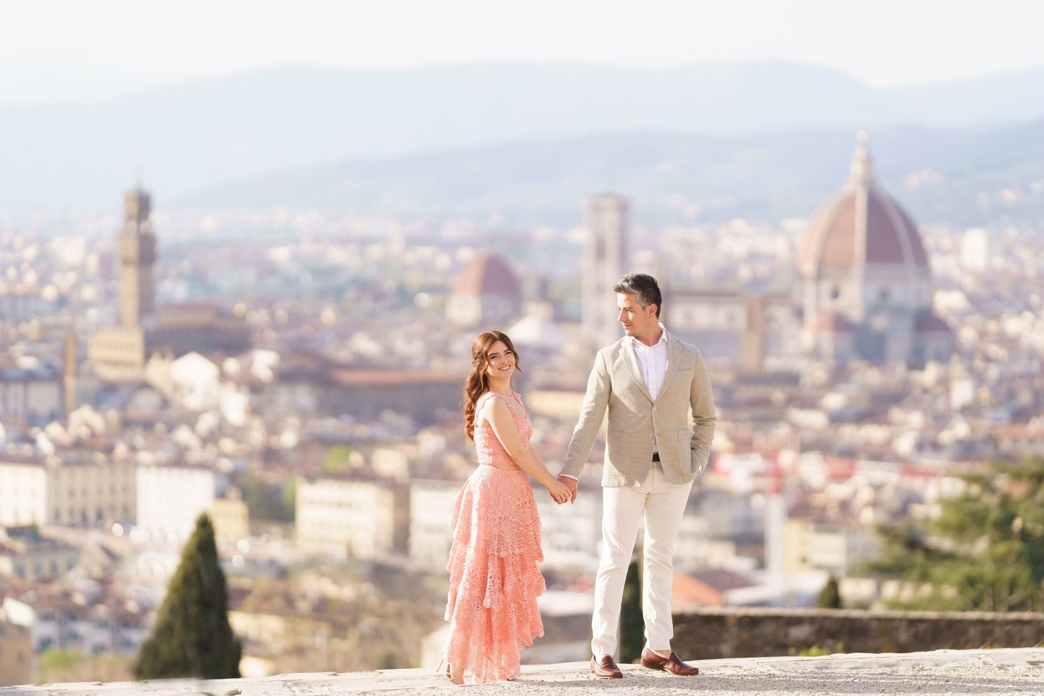 A romantic couple poses for photos with the stunning Florence cityscape and Duomo cathedral in the background.