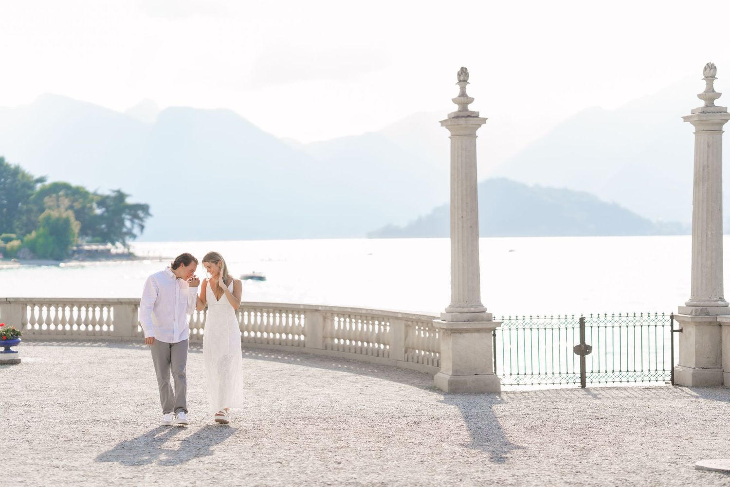 Couple enjoying a romantic moment at a seaside terrace with white columns overlooking the Mediterranean coast.