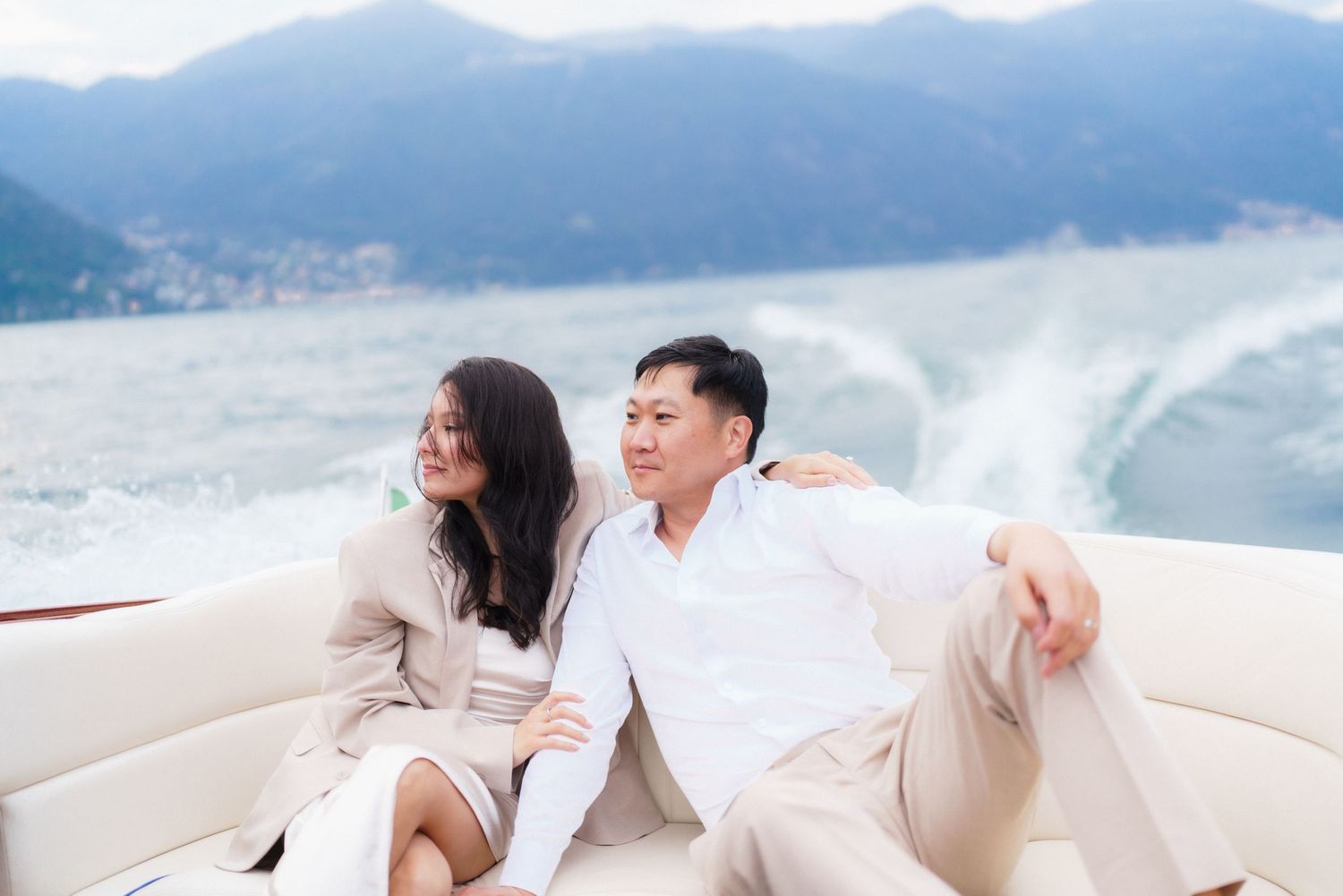 A couple in white attire shares romantic moments by the ocean during a coastal photo session.