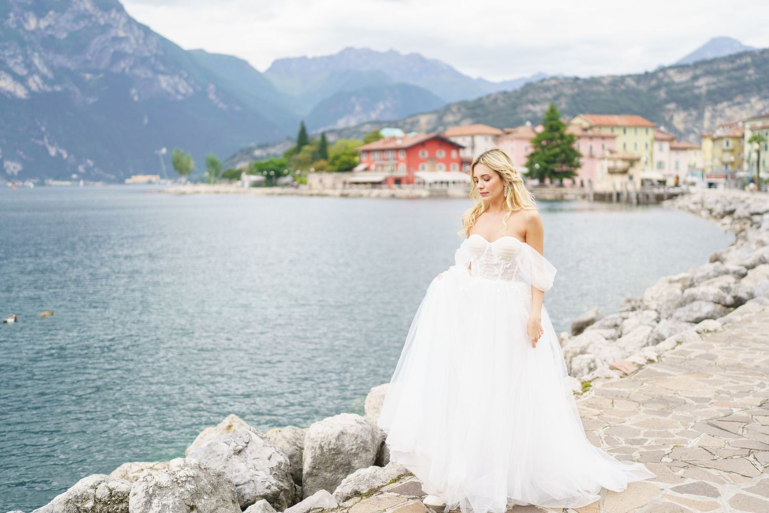 A scenic wedding photoshoot on the shores of Lake Garda in Italy with majestic mountains in the background.