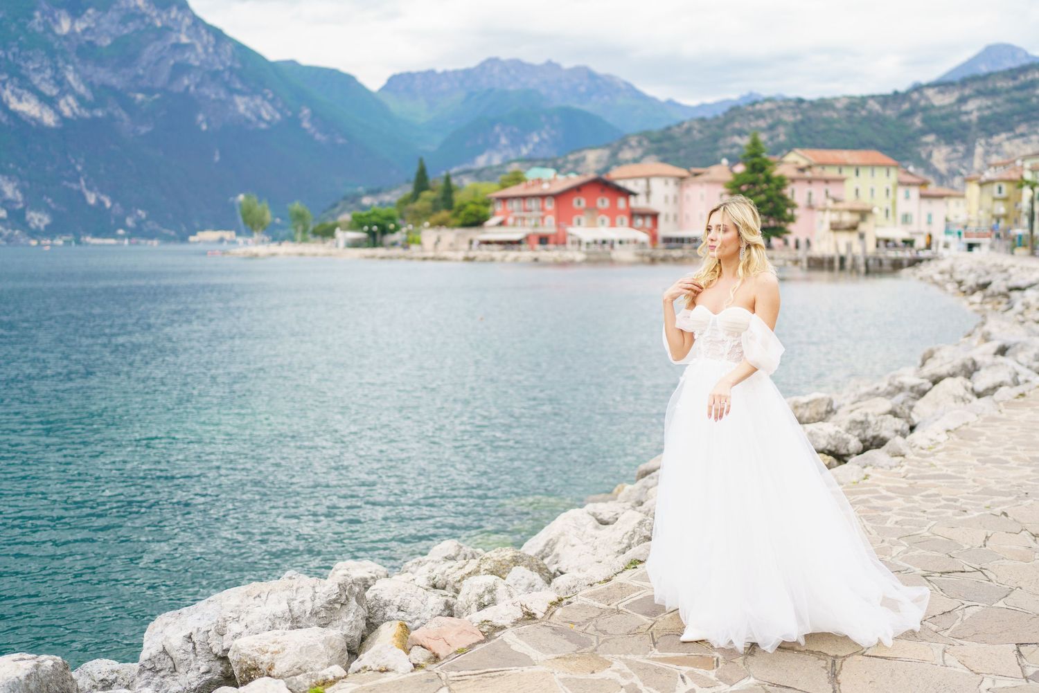 Scenic mountain views along Lake Garda in Italy with coastal buildings and rocky shoreline during summer.