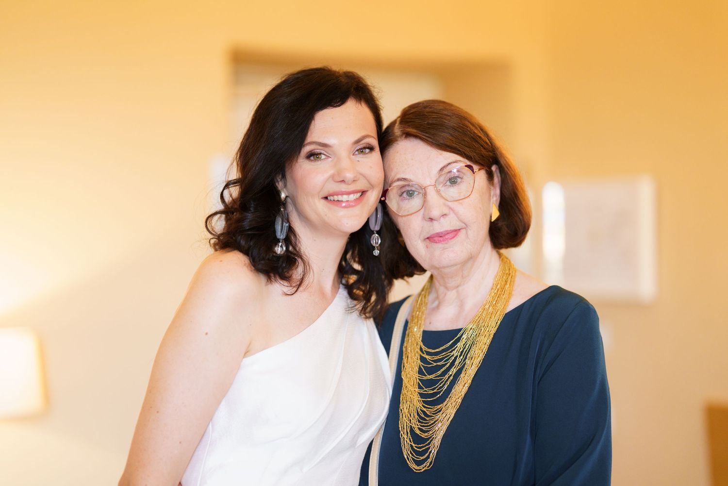 Two people embracing warmly in formal attire at an indoor event.