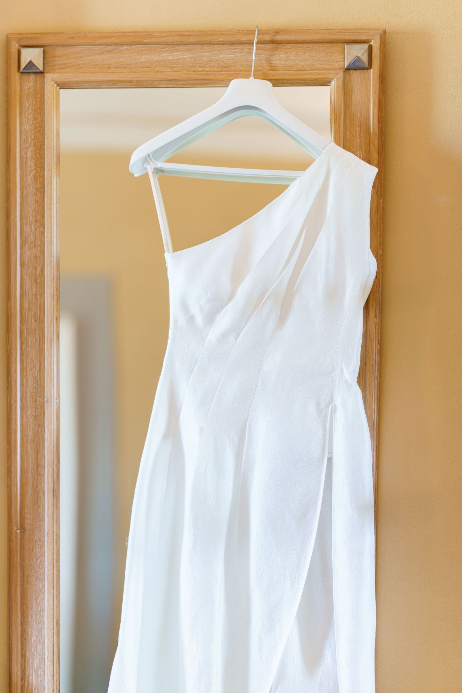 White bridesmaid dresses hanging in a row on wooden hangers.