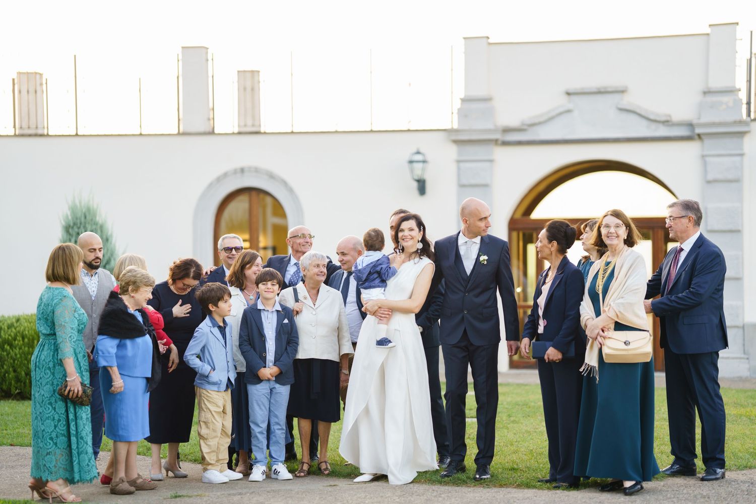 Wedding party members arranged in front of white church building for formal photographs.