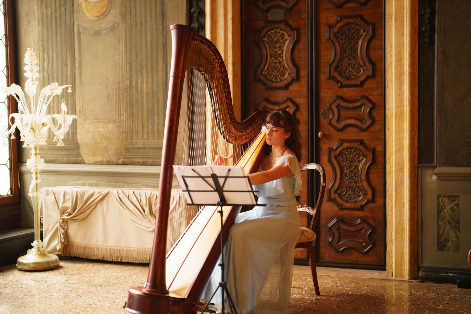 Two ornate golden harps stand in an elegant room with carved wooden panels and classical architectural details.