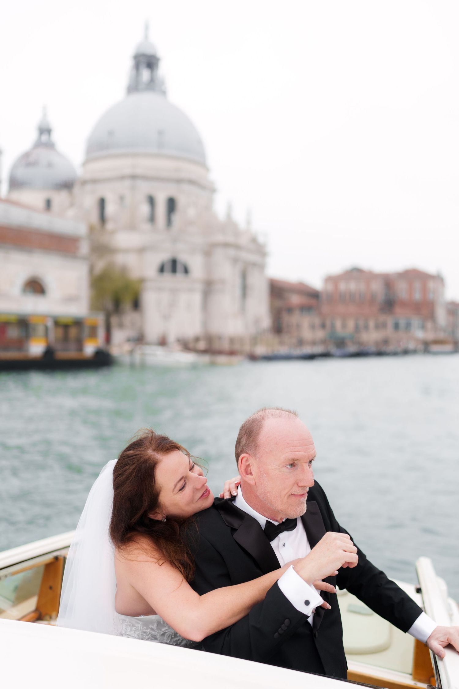 Couple shares romantic moments in a water taxi on Venice's Grand Canal with the Santa Maria della Salute church in background.