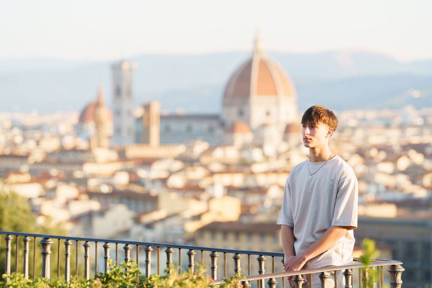 People admiring the stunning panoramic cityscape of Florence, Italy from Piazzale Michelangelo viewpoint at sunset.