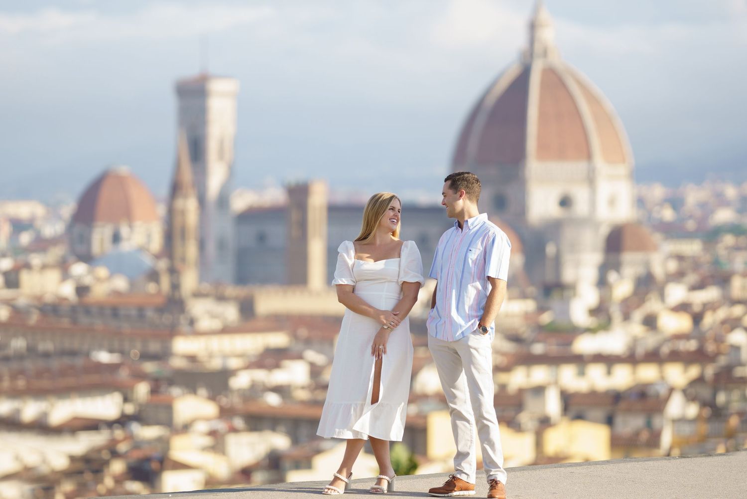 A couple enjoys a romantic moment overlooking the iconic skyline of Florence, Italy with its famous Duomo cathedral.