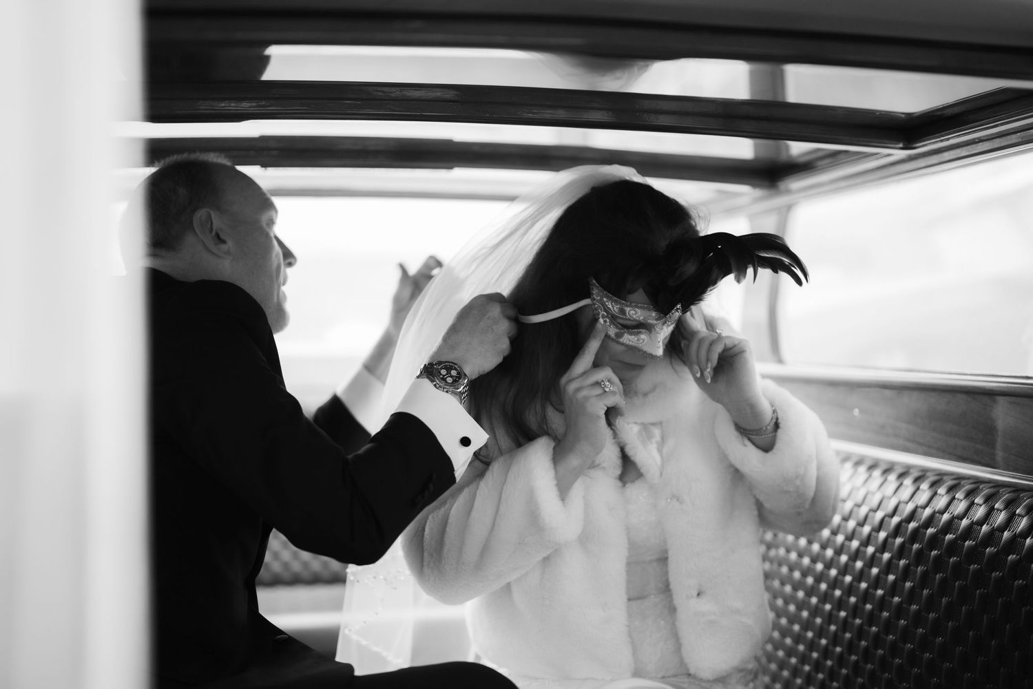 Black and white photo of a couple kissing in a car after their wedding ceremony.