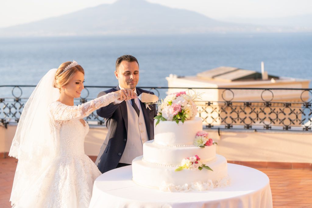 Elegant wedding celebration on a scenic terrace overlooking the Amalfi Coast at sunset.