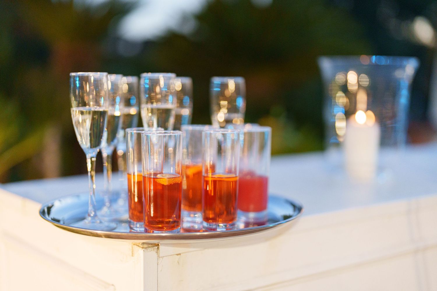 Row of orange cocktails served on silver tray at elegant outdoor event.