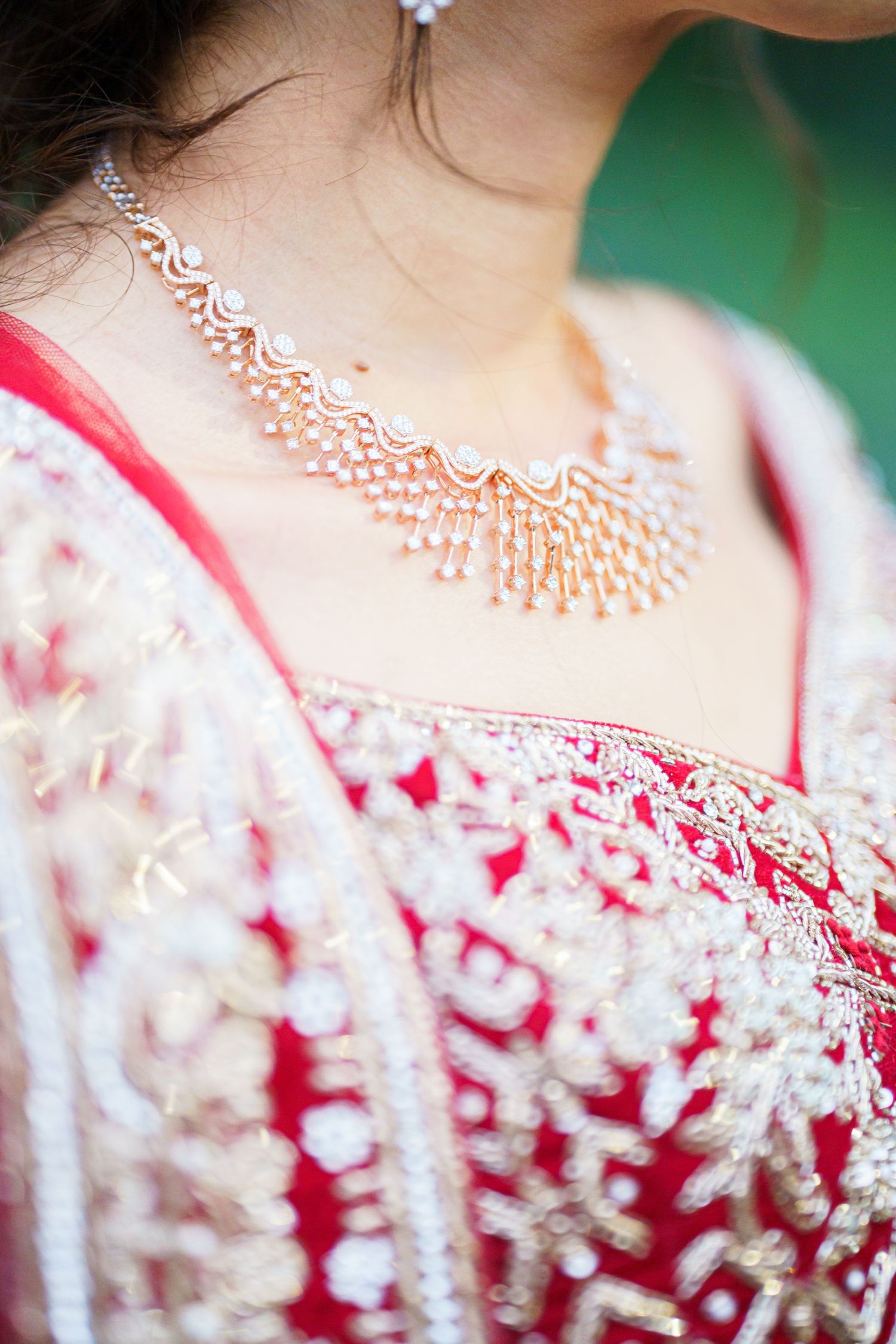 Close-up detail of ornate bridal jewelry and embellished red wedding attire.