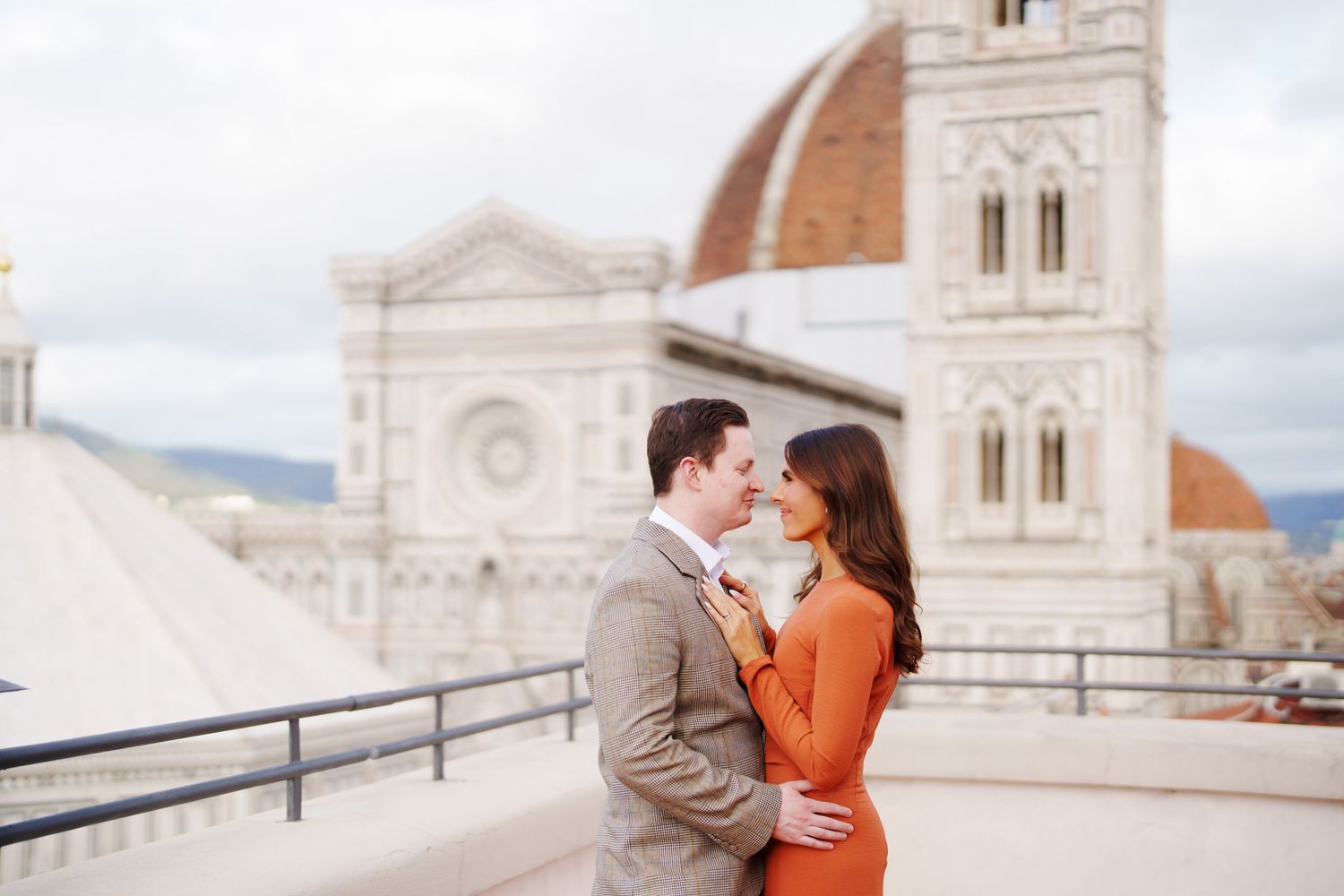 Couple embracing romantically on a rooftop terrace with Florence Cathedral dome backdrop in Italy.