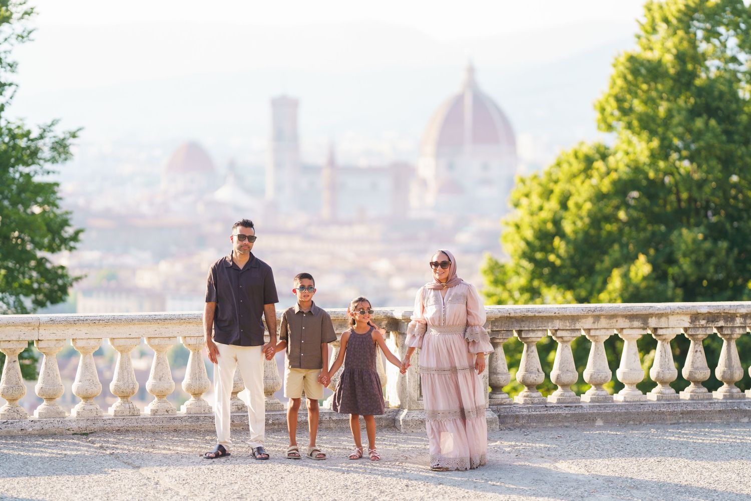 Family of four posing on a terrace in Florence, Italy, with the iconic Duomo cathedral visible in the background.