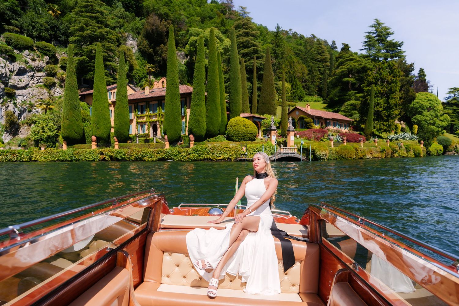 Luxury Lake Como boat photoshoot with elegant woman surrounded by Italian villas and cypress trees