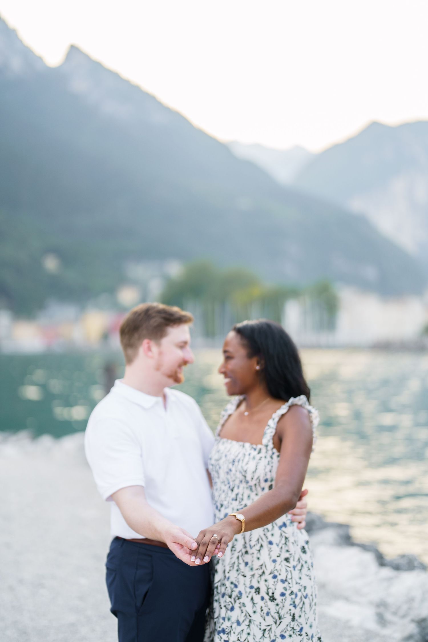 Smiling interracial couple embracing and holding hands by a beautiful mountain lake.