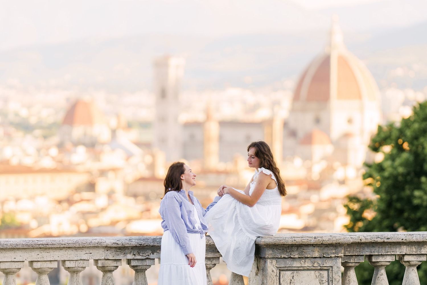 A couple enjoys a romantic moment overlooking a scenic European city view from a stone balcony.