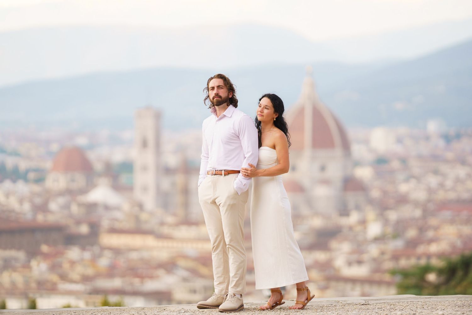 Couple enjoying scenic view of Florence cityscape with Duomo cathedral from hilltop overlook.
