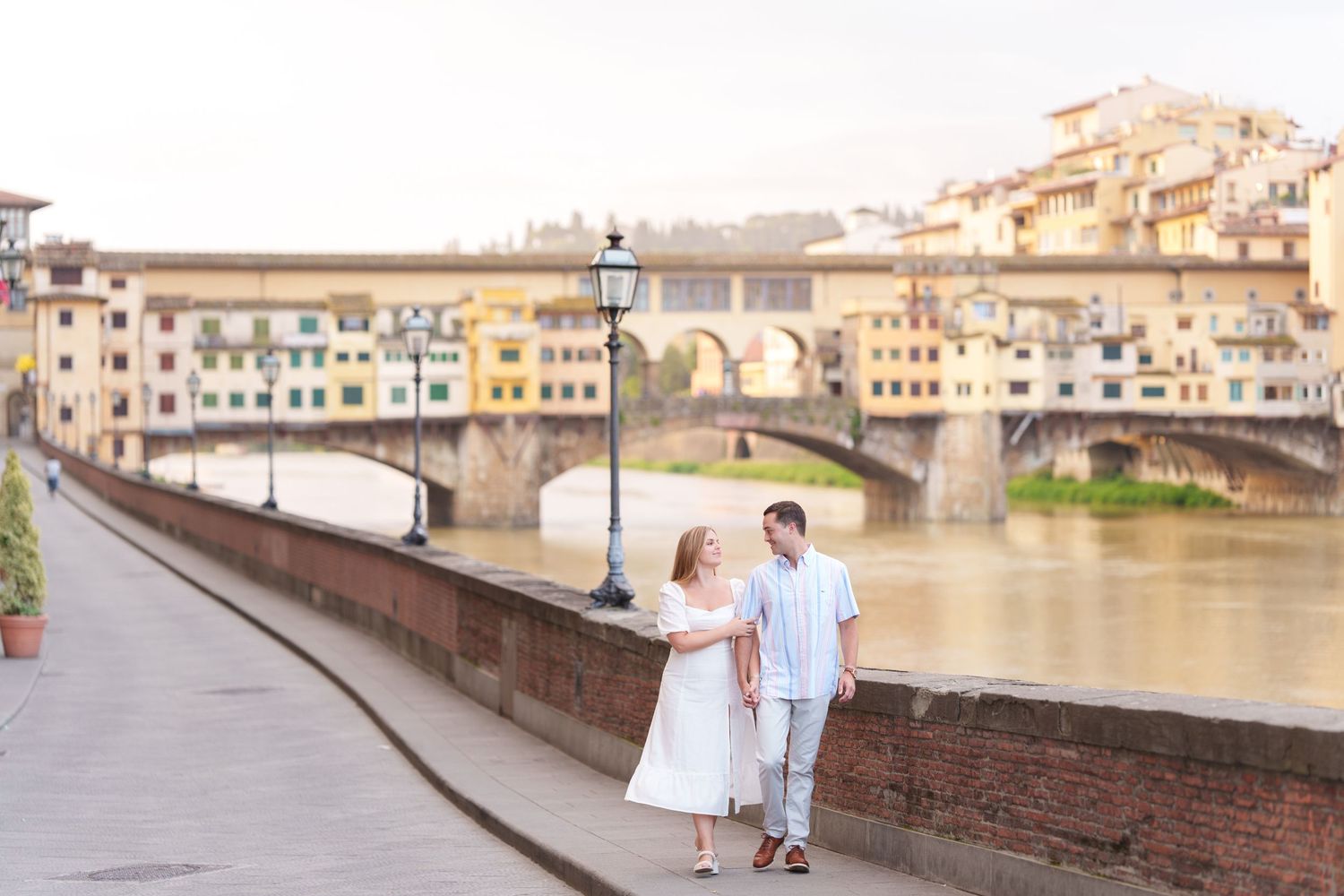 Scenic view of Florence's Ponte Vecchio bridge and historic buildings reflecting in the Arno River at sunset.