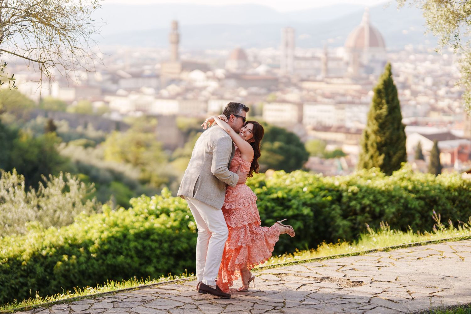 A couple shares a romantic moment at sunset overlooking the Florence cityscape from Piazzale Michelangelo.