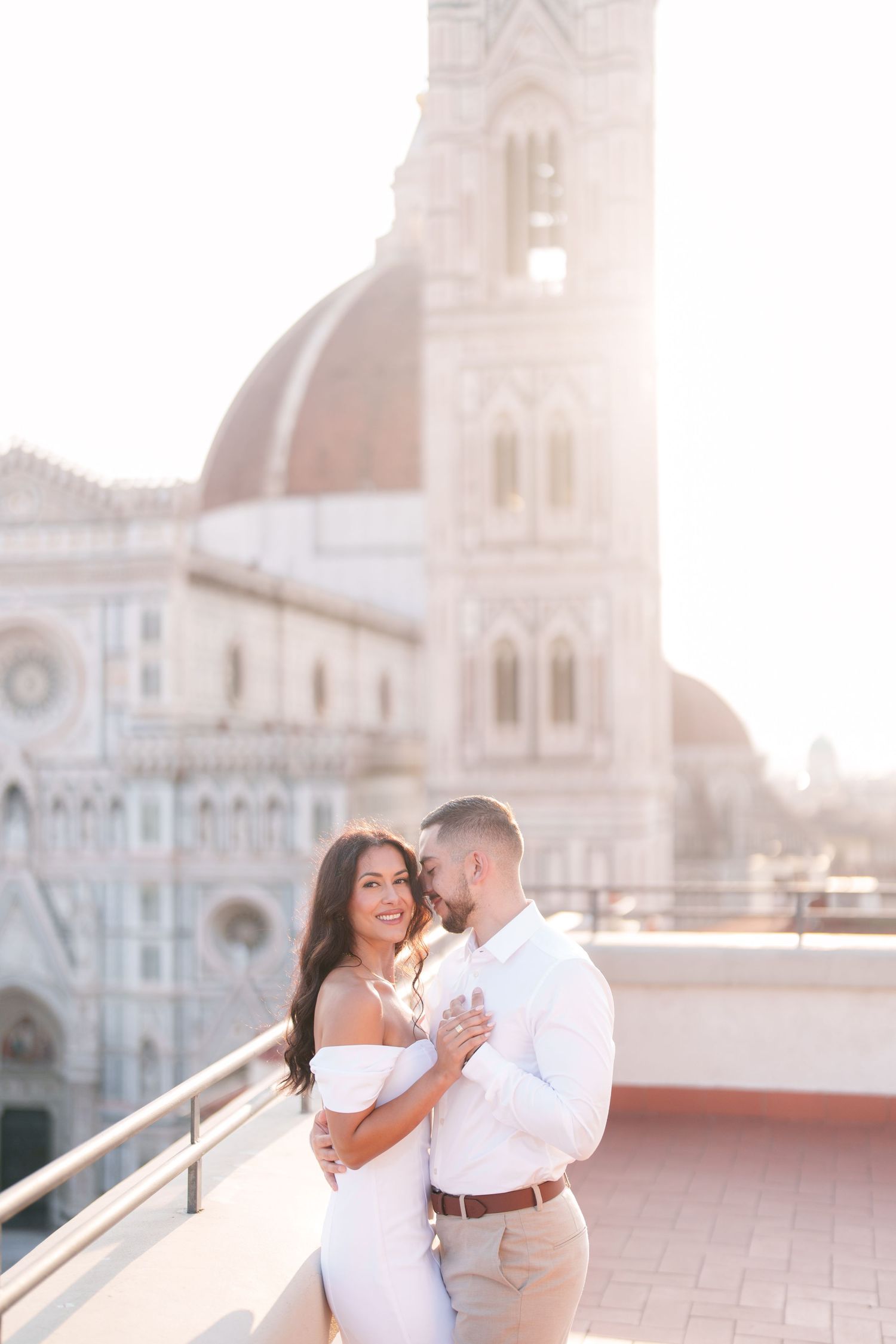 A romantic couple shares an intimate moment on a rooftop terrace with a beautiful cathedral backdrop in Florence, Italy.