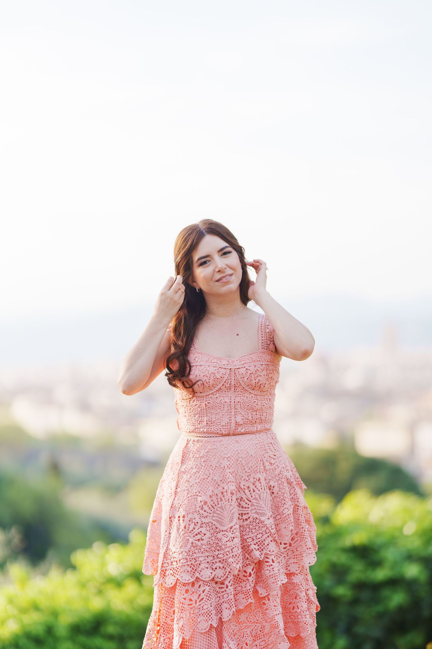 A woman in a peach lace dress poses outdoors against a blurred natural background in a series of photos.