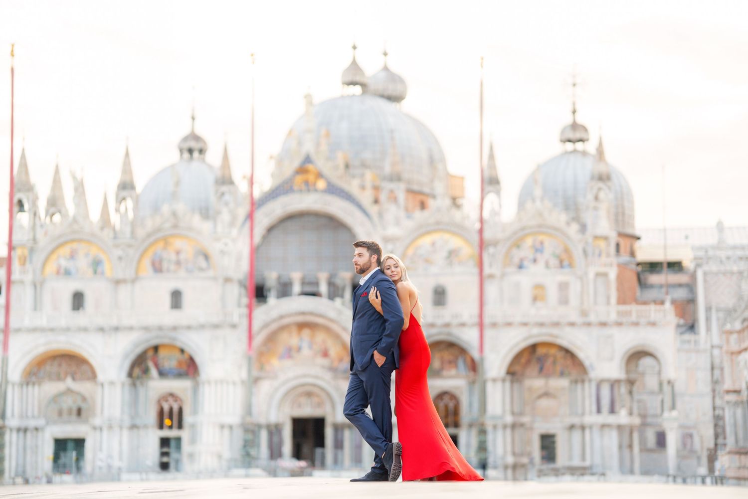 Couple in formal attire poses in front of Saint Mark's Basilica in Venice during a romantic photoshoot.