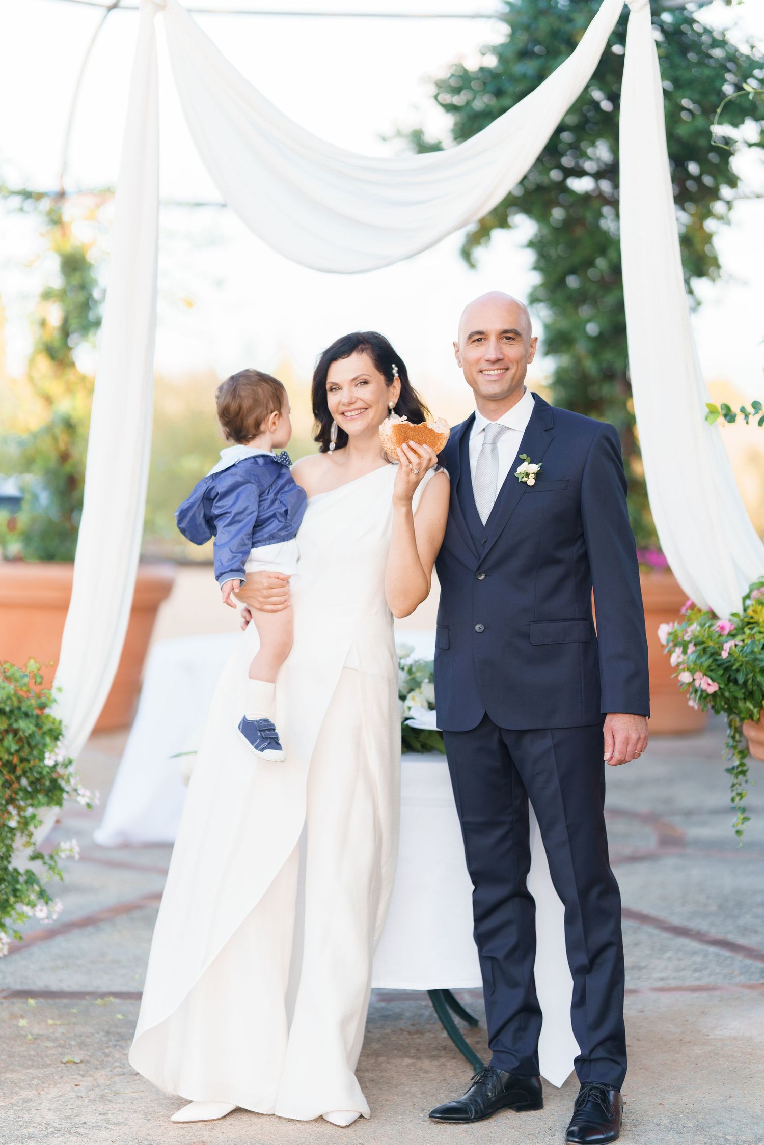Wedding celebration photos taken under white draped canopy in outdoor garden venue.