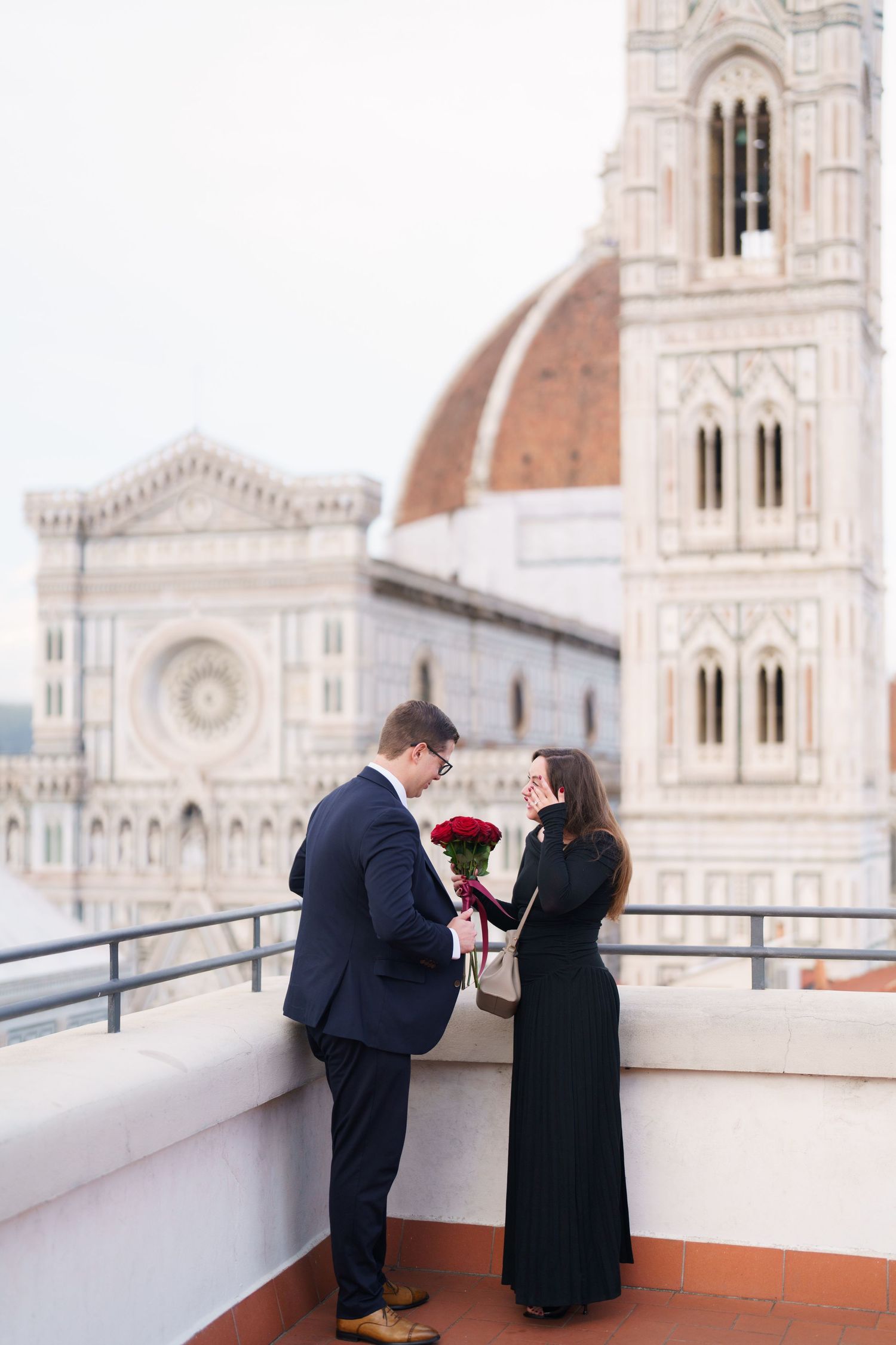 A romantic couple shares an intimate moment on a rooftop terrace overlooking Florence Cathedral in Italy.