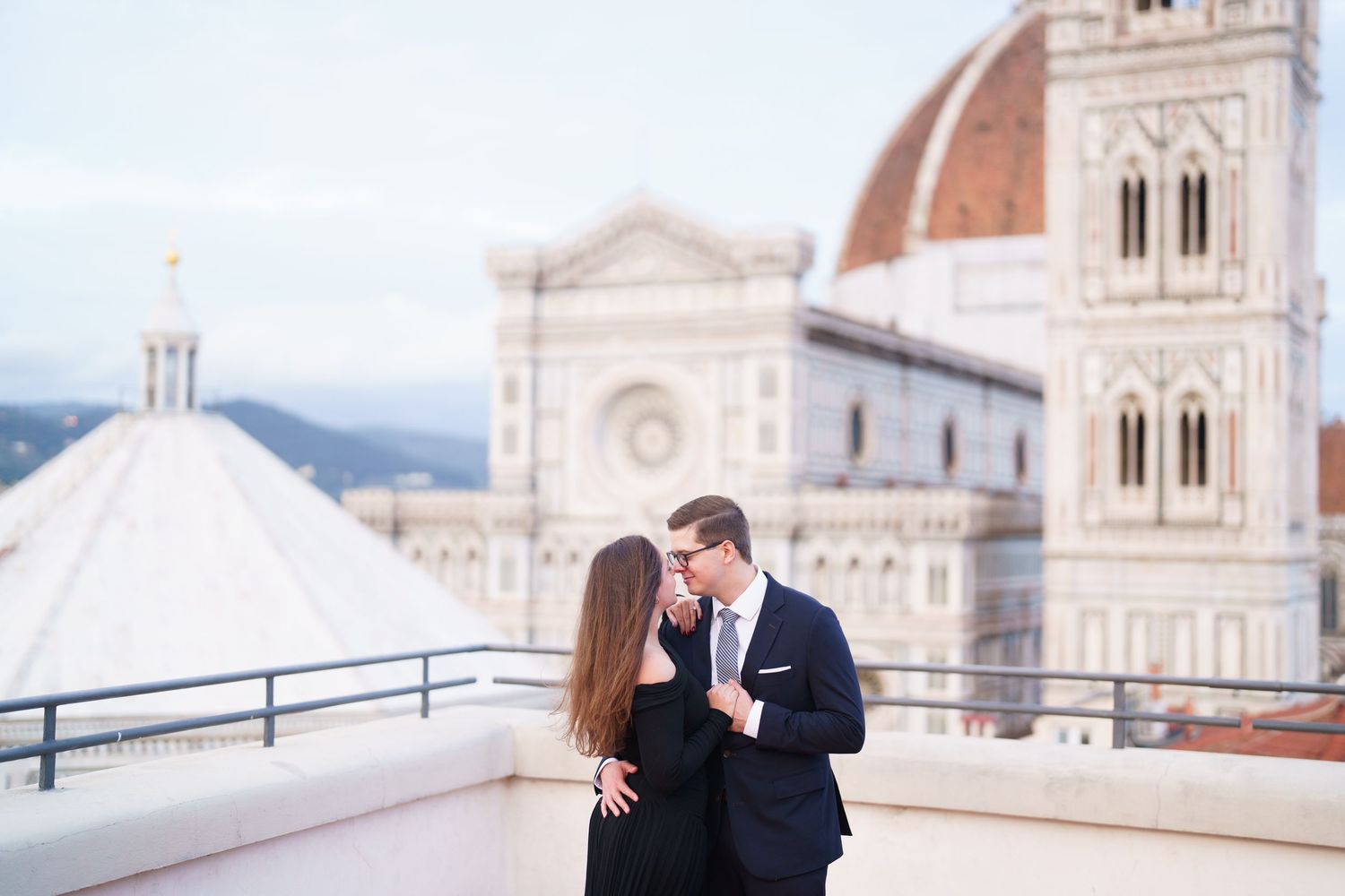 A couple shares a romantic moment on a rooftop terrace overlooking the Florence Cathedral and Duomo in Italy.