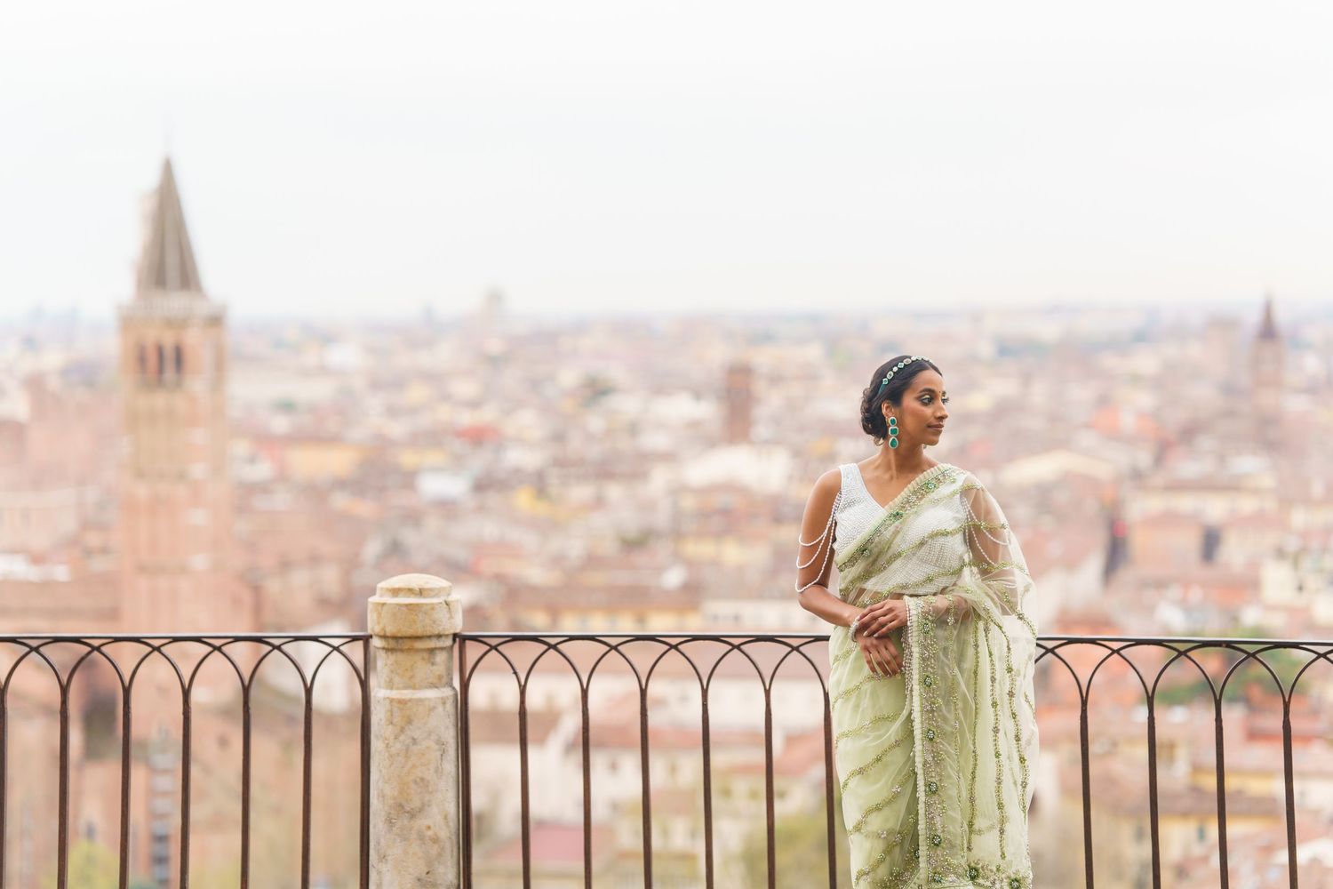 Person in light green dress admires panoramic cityscape view of Bologna, Italy from elevated viewpoint.