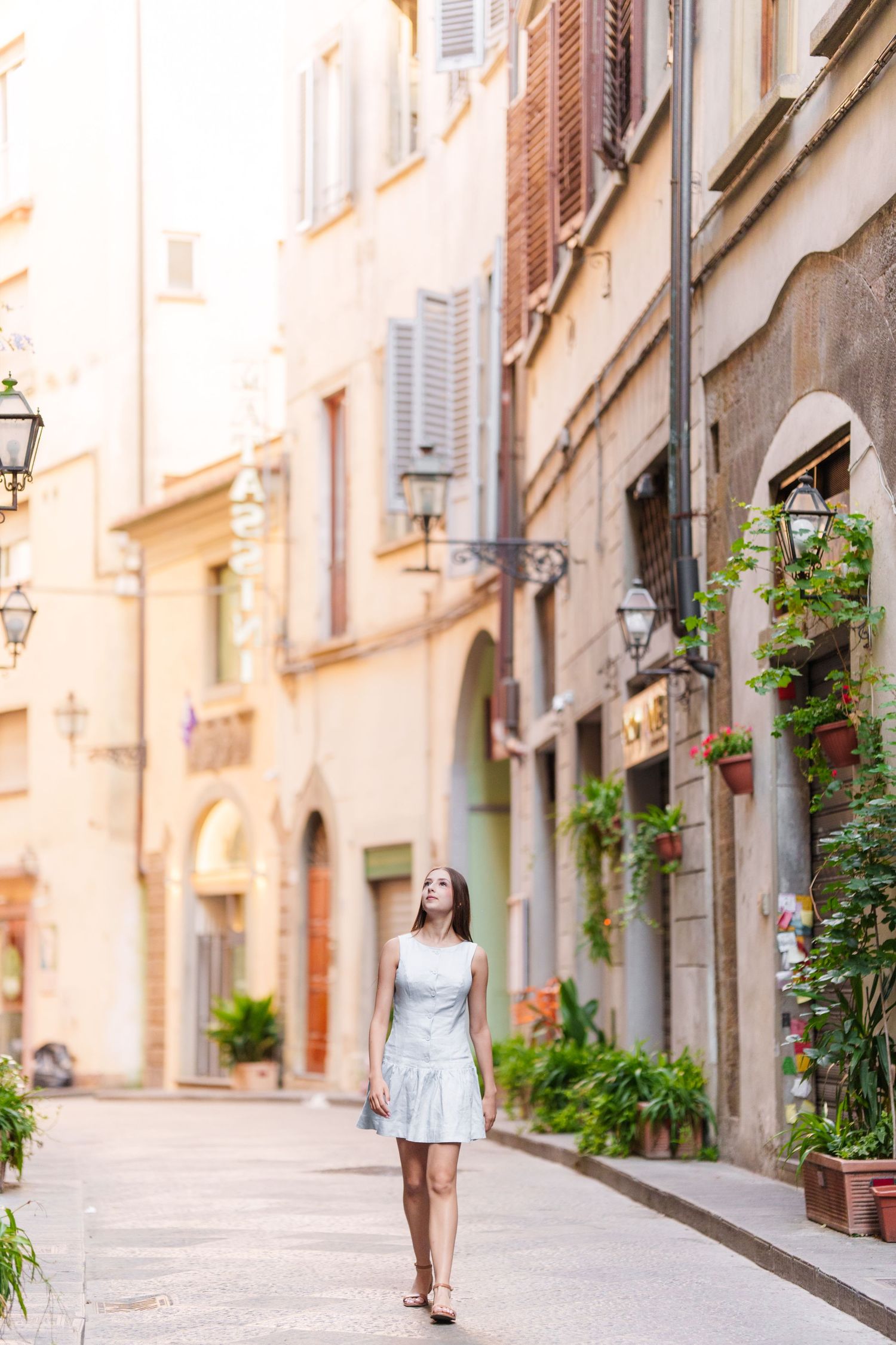 Charming narrow cobblestone street in an old European town with traditional buildings and window shutters in warm sunlight.