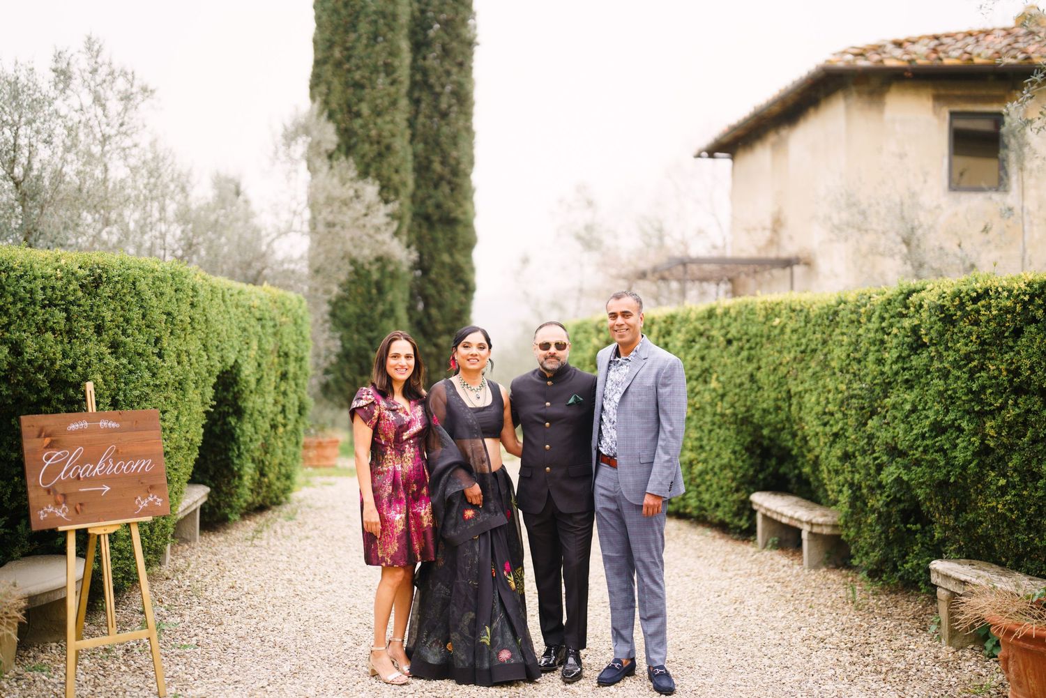 Group photo on a landscaped path with cypress trees and decorative wooden signs.
