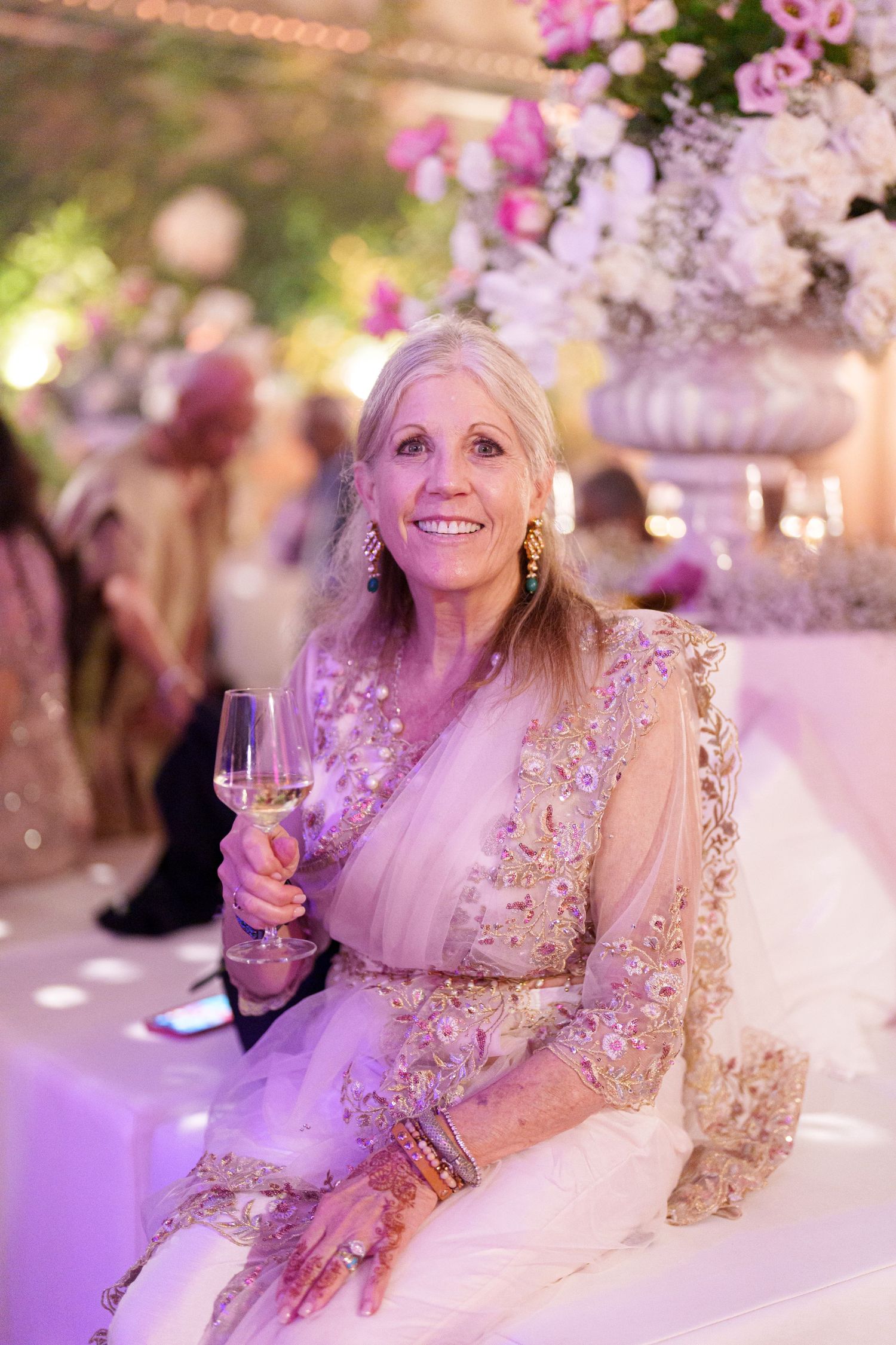 Elegant reception setting with pink floral arrangements and soft purple lighting creating a romantic atmosphere.