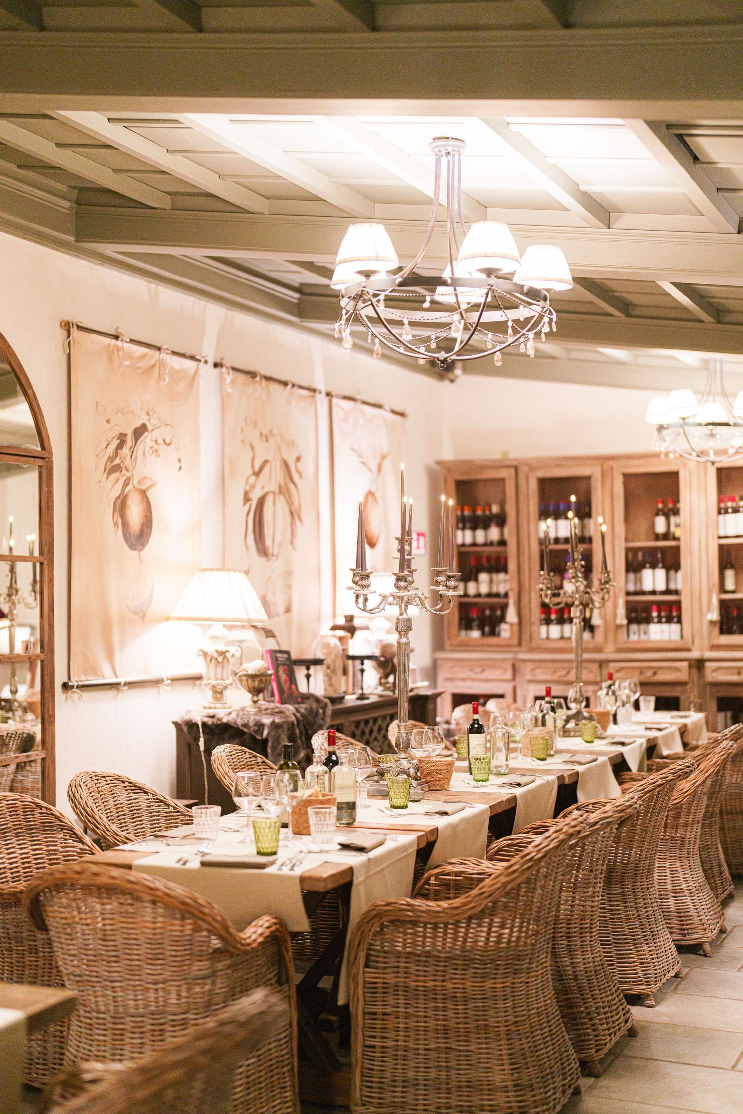 Luxurious dining room with wicker chairs, wine display and coffered ceiling.