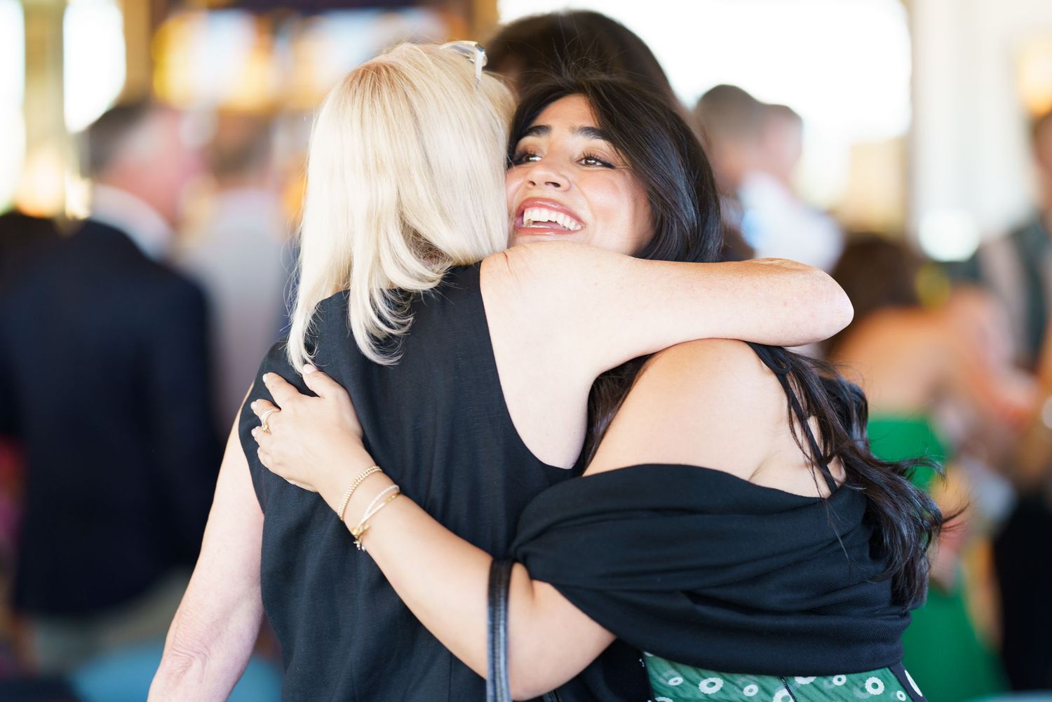 Two people sharing an emotional embrace at an indoor social event.