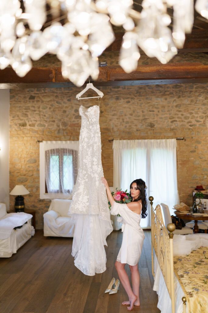 Wedding dress displayed in rustic venue with stone walls and exposed wooden beams.