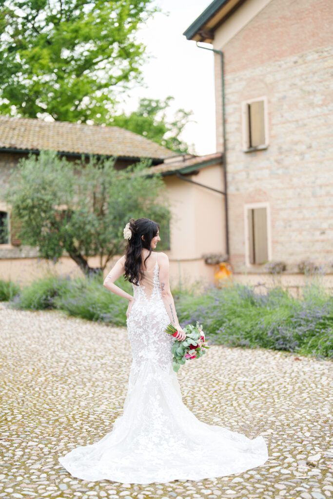 A beautiful wedding dress with a long train flows across a cobblestone courtyard at an Italian villa.