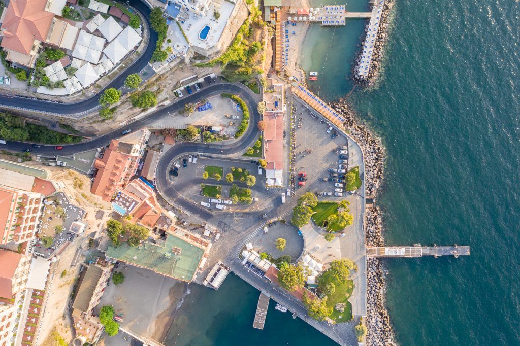 Aerial view of a Mediterranean harbor with boats, docks, and coastal buildings.