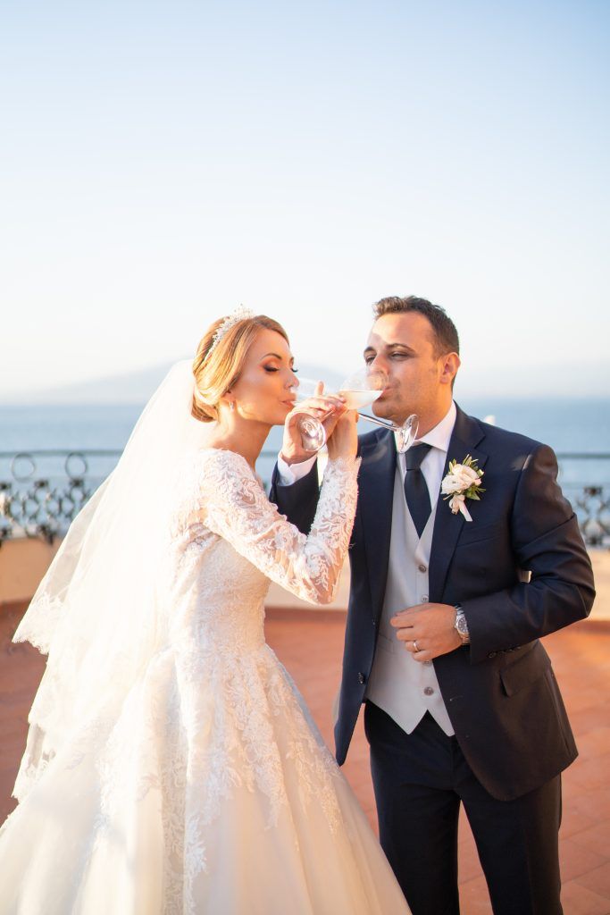 Romantic wedding couple sharing a moment against an ocean backdrop.