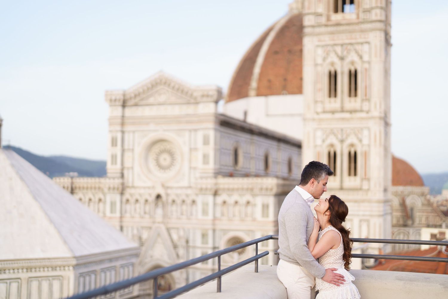 A couple embraces on a rooftop terrace overlooking the historic Florence Cathedral and Duomo in Italy.