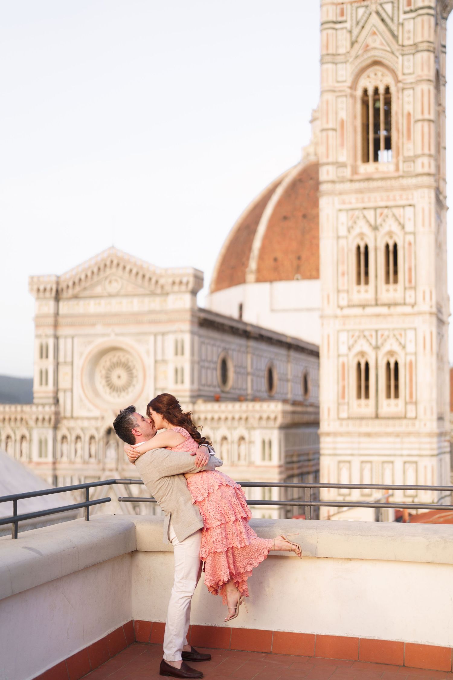 Couple in romantic poses against the backdrop of Florence Cathedral's ornate architecture during sunset.