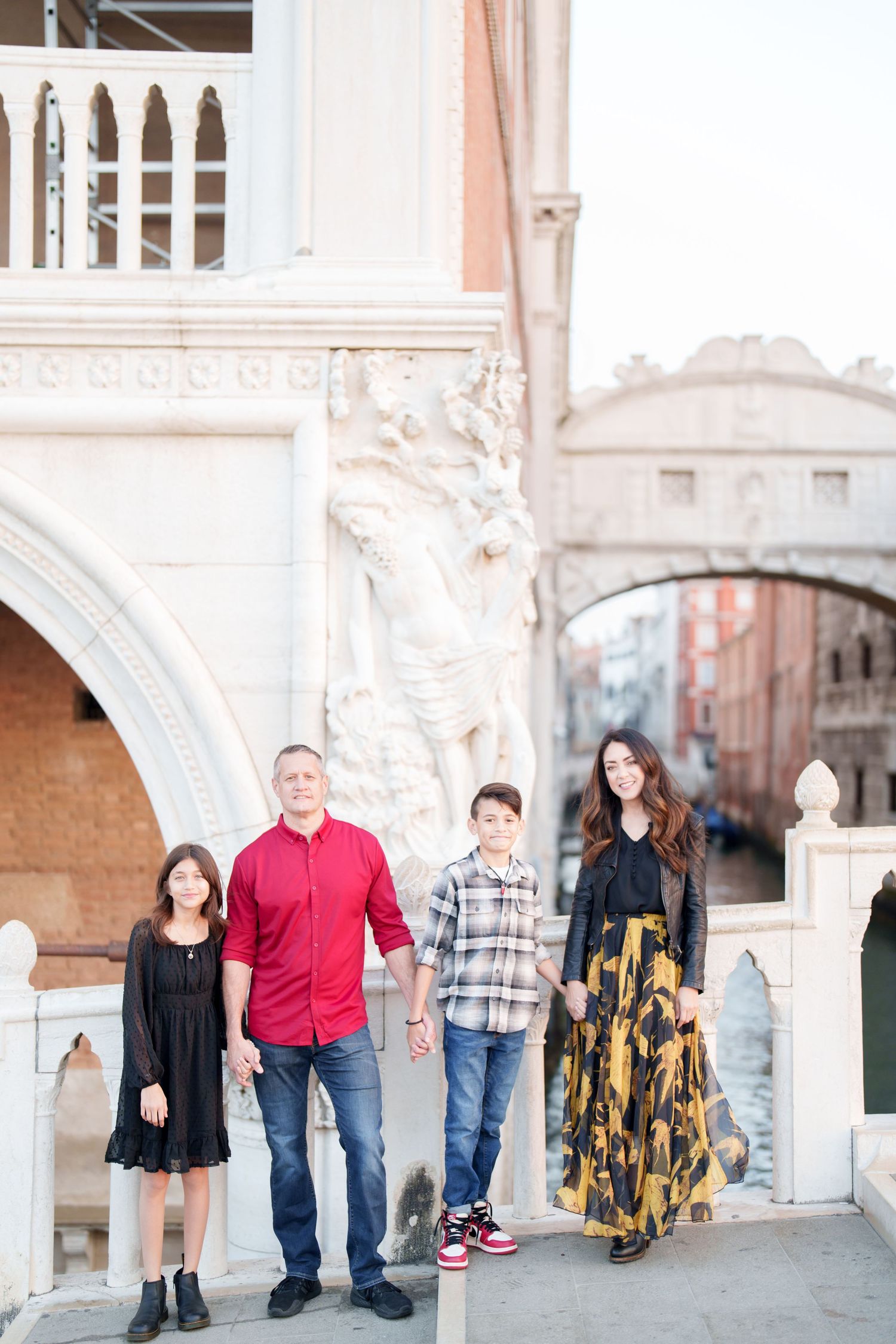 Family portrait session in Venice with elegant arched architecture and classic Italian buildings in the background.