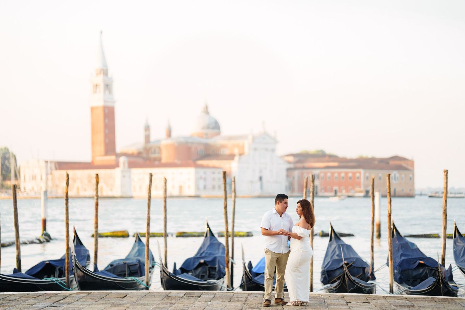 photographer veniceRow of moored gondolas along Venice canal with San Giorgio Maggiore church in the background during golden hour.