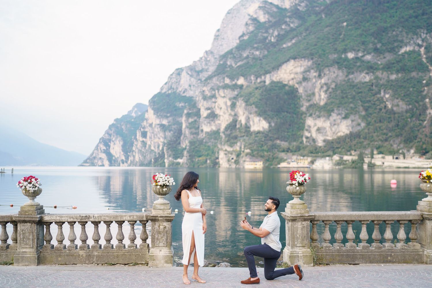 A scenic lakeside walkway with stone balustrade overlooking mountains and calm waters in Lake Como, Italy.