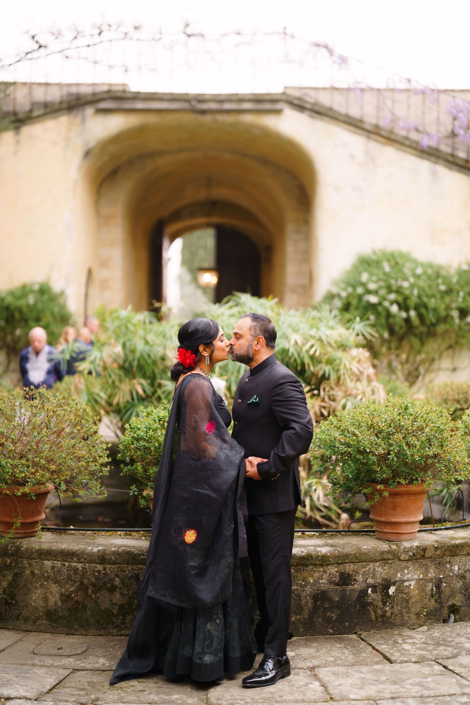 Couple sharing romantic moment by garden terrace with potted plants.