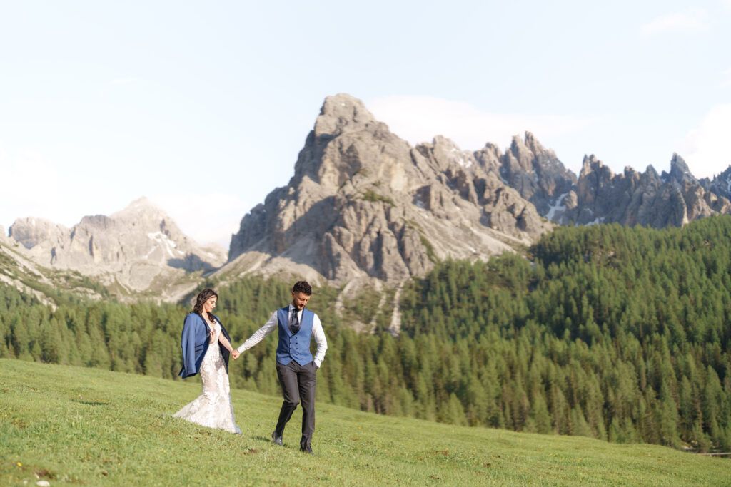 A couple shares an intimate moment on a mountain meadow with dramatic Dolomite peaks in the background.