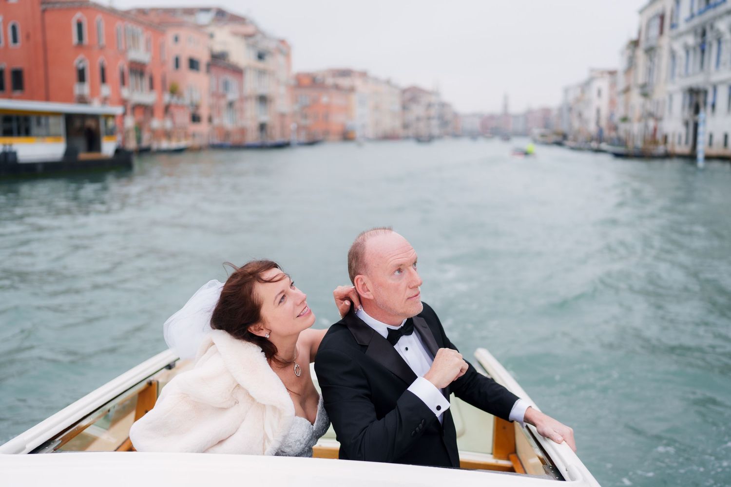 Two people enjoy a romantic boat ride through the scenic canals of Venice, Italy on a sunny afternoon.