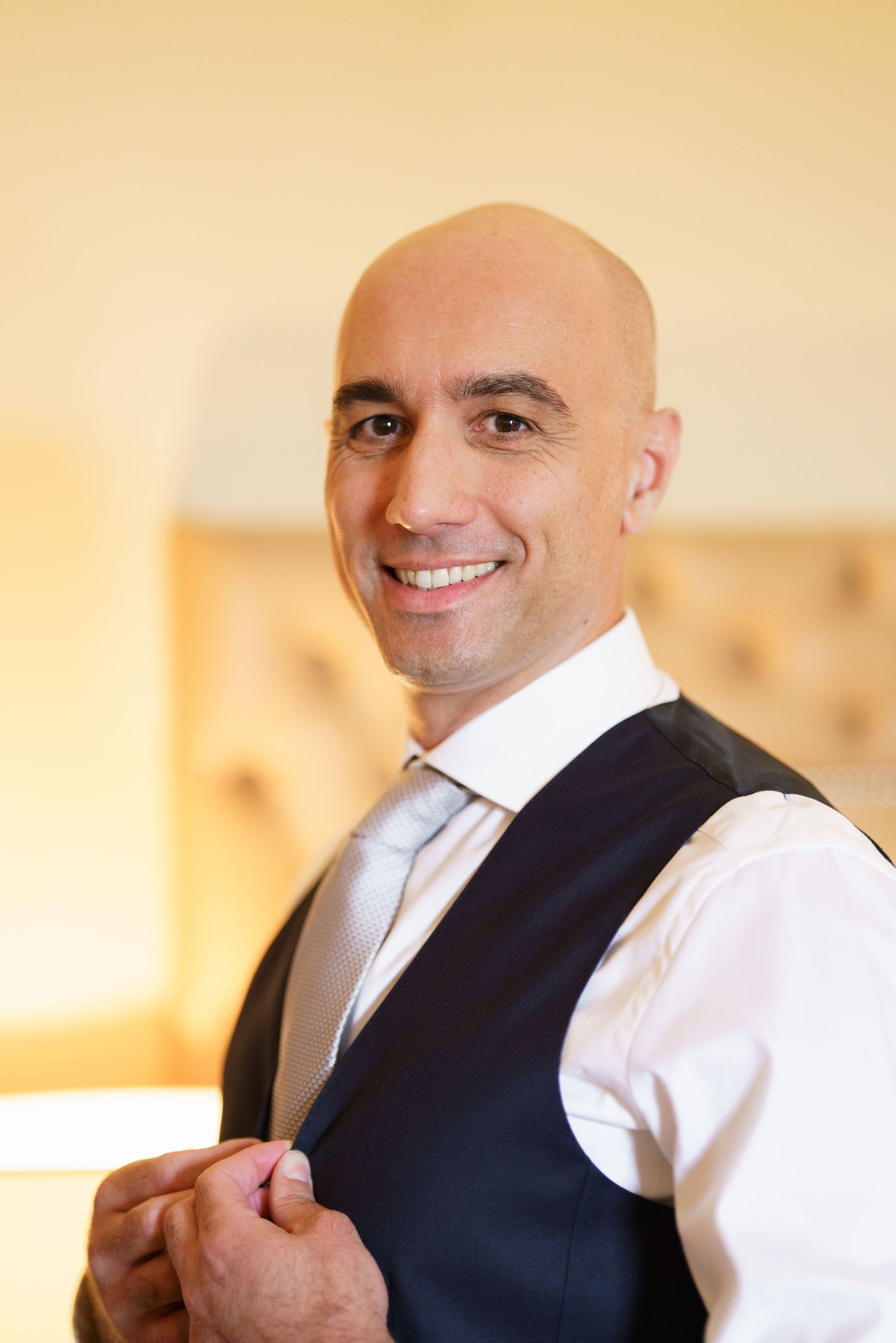Sequence of man in formal attire adjusting vest while smiling.